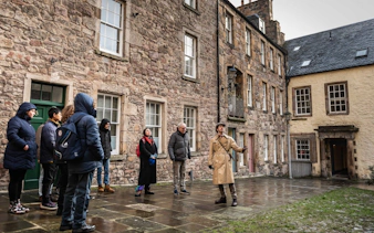 Tour group exploring historical buildings in Edinburgh with a guide.
