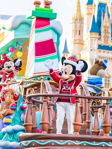 Mickey and Minnie Mouse on a festive parade float at Tokyo Disneyland with Cinderella Castle in the background.