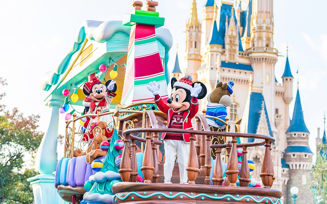 Mickey and Minnie Mouse on a festive parade float at Tokyo Disneyland with Cinderella Castle in the background.