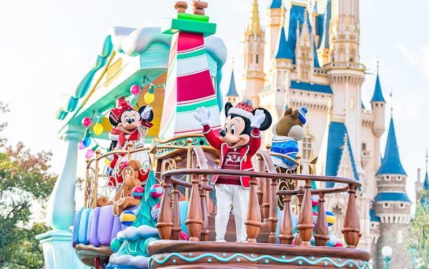 Mickey and Minnie Mouse on a festive parade float at Tokyo Disneyland with Cinderella Castle in the background.