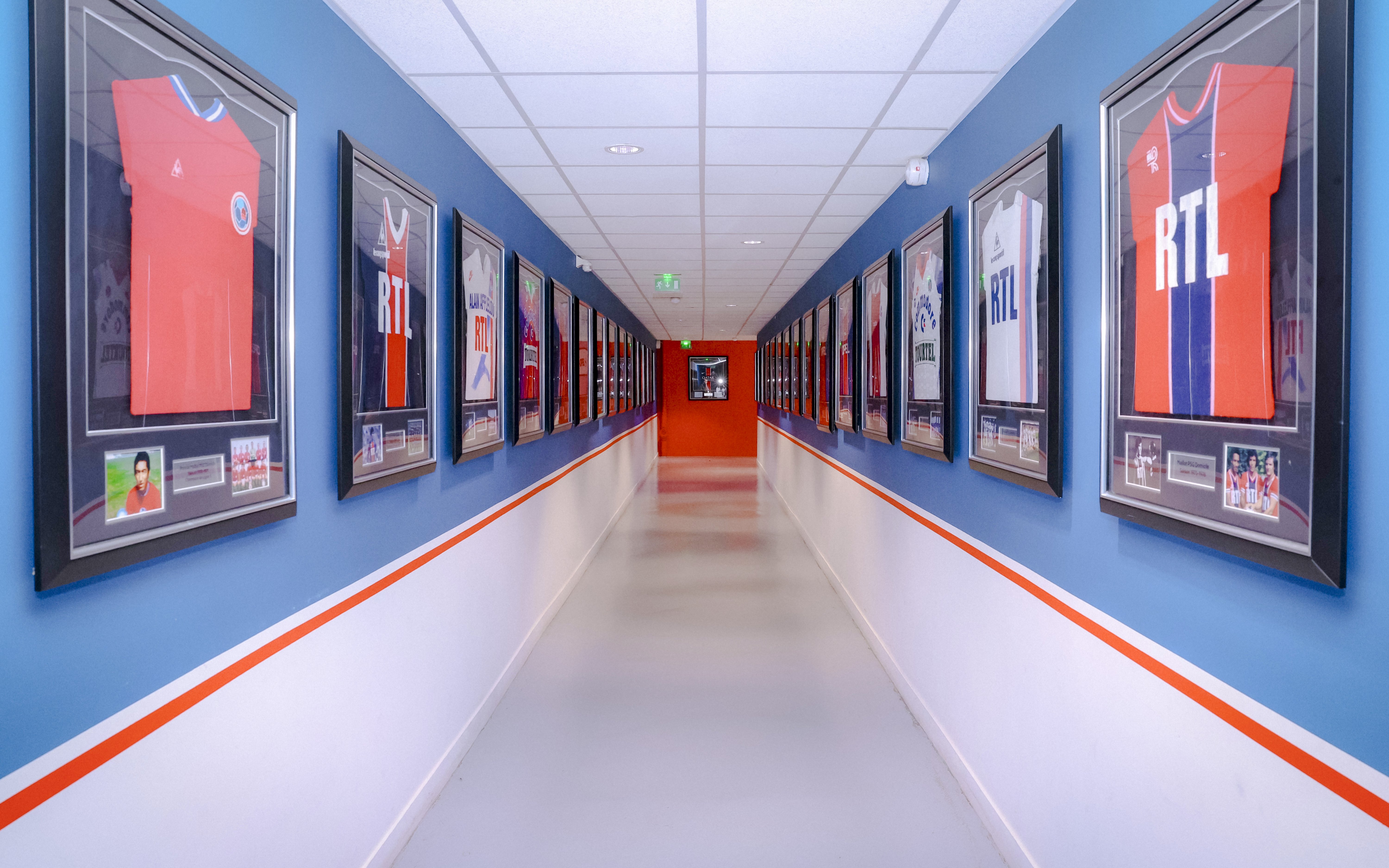 Framed PSG jerseys displayed in a hallway at PSG Stadium, Paris, France.