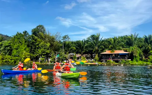 Kayakers paddling on a river surrounded by lush greenery in Krabi.