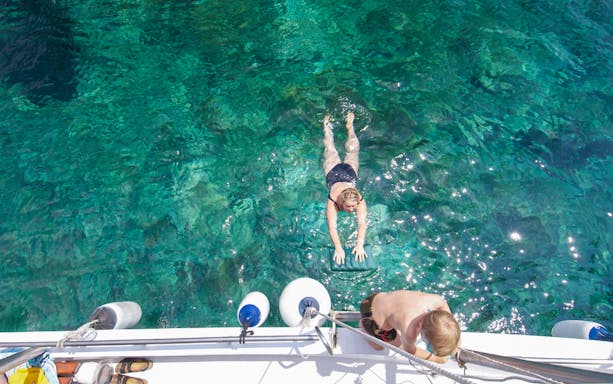 Swimming near a boat in clear waters on Ponza Island day trip from Rome.
