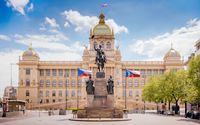 Prague National Museum with equestrian statue and Czech flags in front.