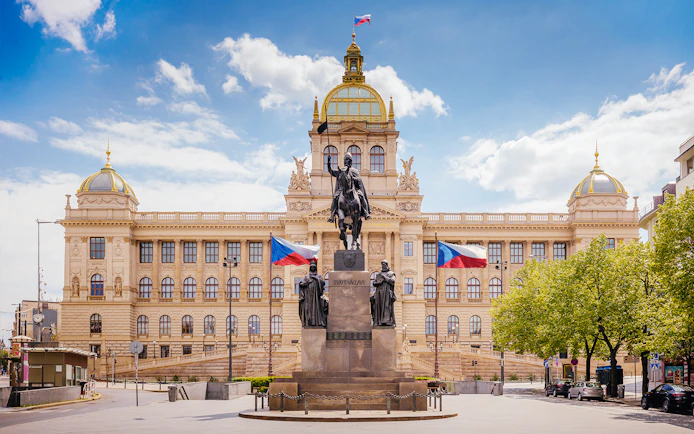 Prague National Museum with equestrian statue and Czech flags in front.