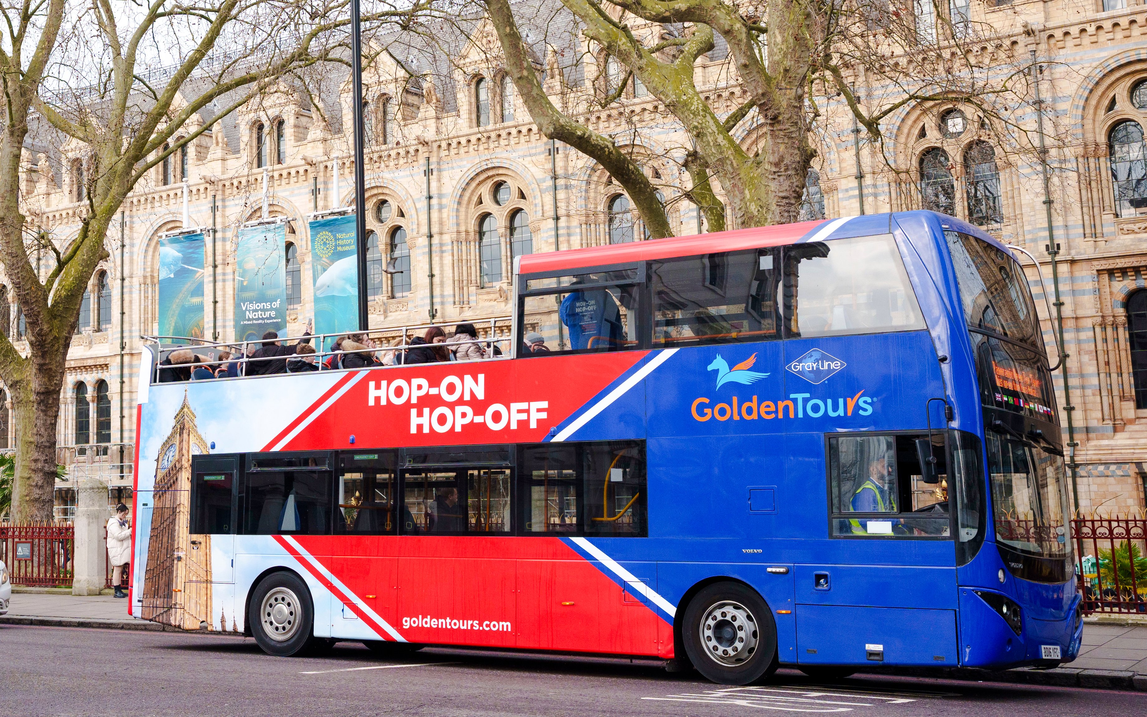 Golden Tours hop-on hop-off bus in front of a historic building in London.