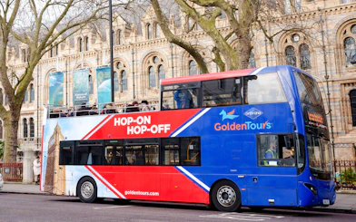 Golden Tours hop-on hop-off bus in front of a historic building in London.
