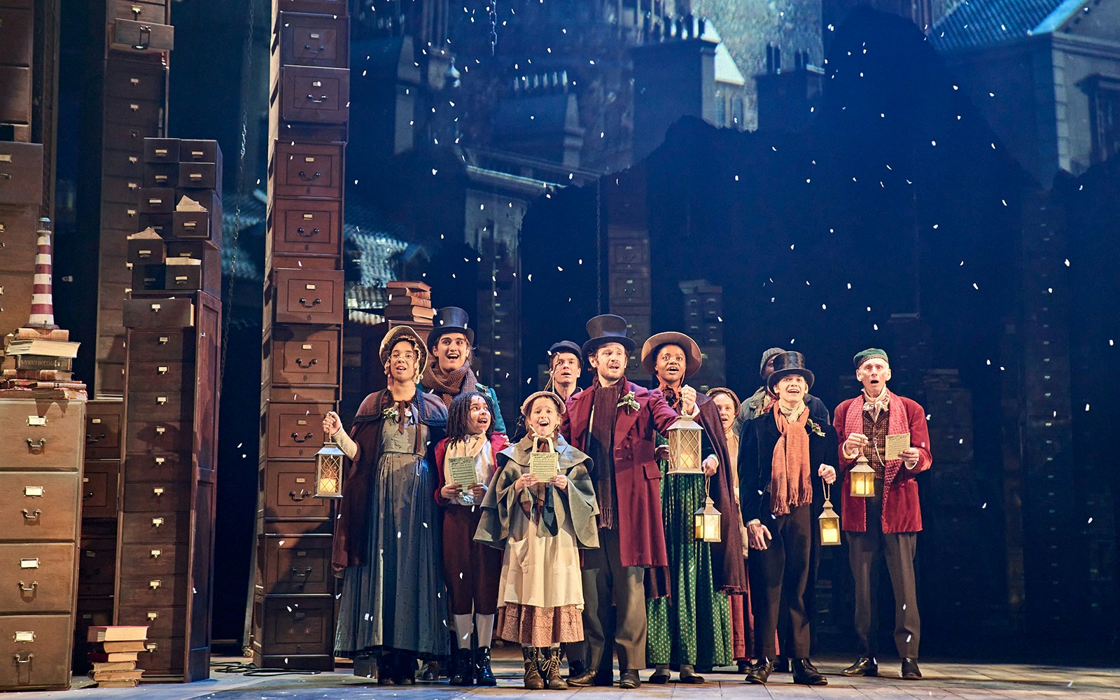 Actors in Victorian costumes holding lanterns on stage during "A Christmas Carol - A Ghost Story" performance.