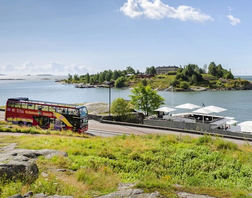 Ônibus turístico de Helsinque perto da orla durante o passeio Hop-on Hop-off.