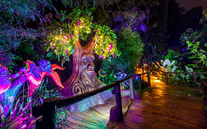 Illuminated tree sculpture and vibrant plants at Lost World Hot Springs Night Park.