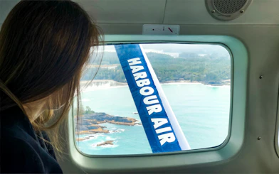 Woman viewing Vancouver coastline from seaplane window on Scenic Panorama Tour.