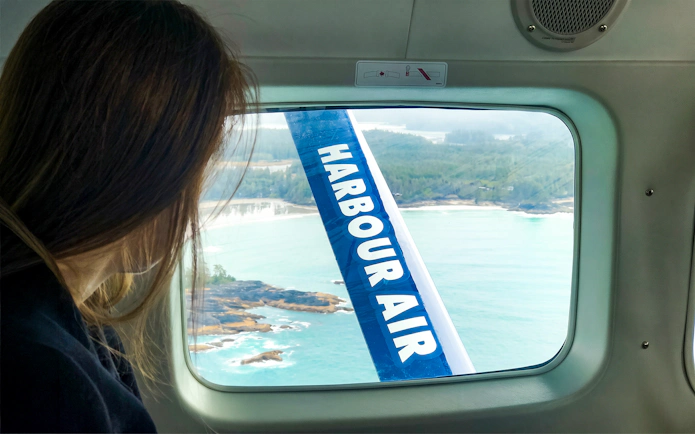 Woman viewing Vancouver coastline from seaplane window on Scenic Panorama Tour.