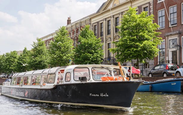 Canal boat cruising past historic buildings in Haarlem.