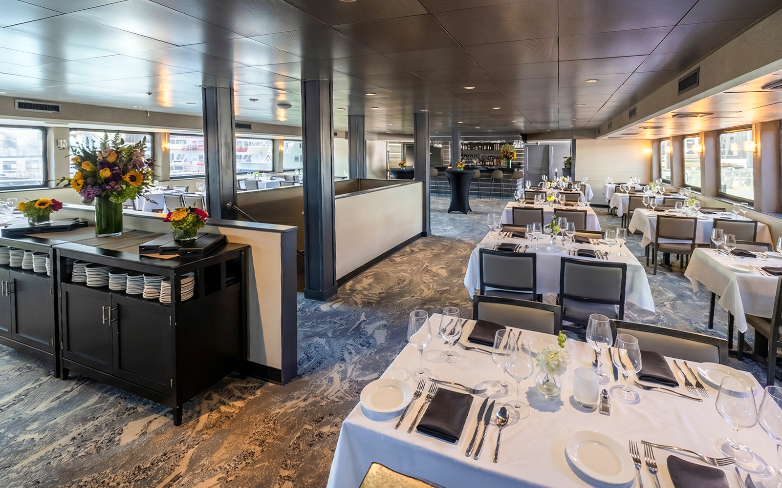 Elegant dining area on Boston Premier Lunch Cruise with set tables and floral arrangements.