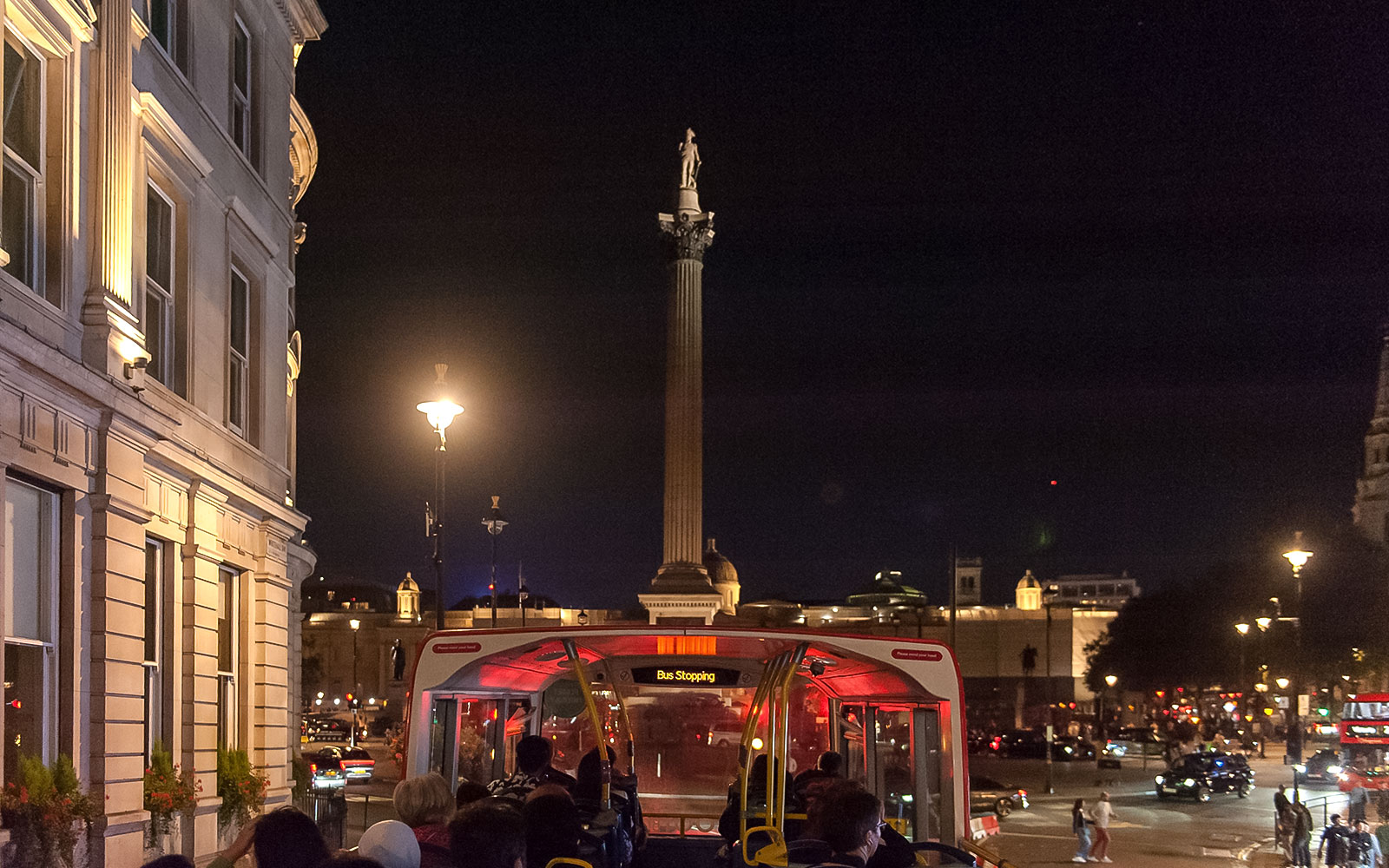 Open-top bus tour at night near Nelson's Column, London.