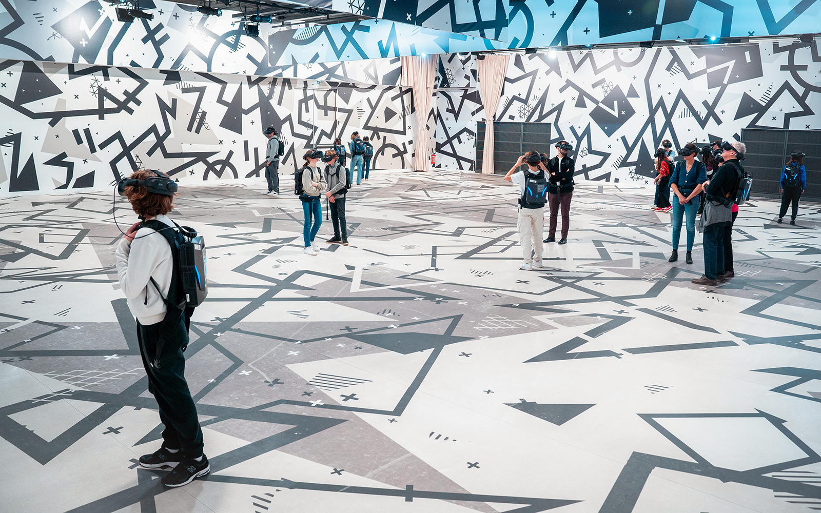 Visitors wearing VR headsets in a geometric-patterned room for the Eternal Notre-Dame VR Experience.