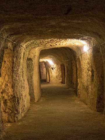 Underground tunnel in Turin with illuminated stone walls.