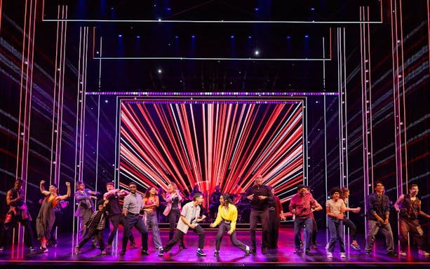 Stage performance of MJ the Musical in Brisbane with dancers in front of vibrant red lights.