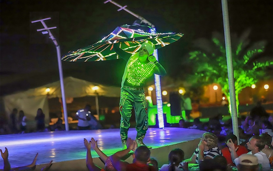 Performer in illuminated costume dancing at Evening Red Dune Desert Safari with BBQ Buffet Dinner.