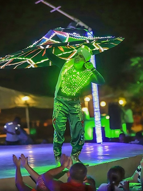 Performer in illuminated costume dancing at Evening Red Dune Desert Safari with BBQ Buffet Dinner.
