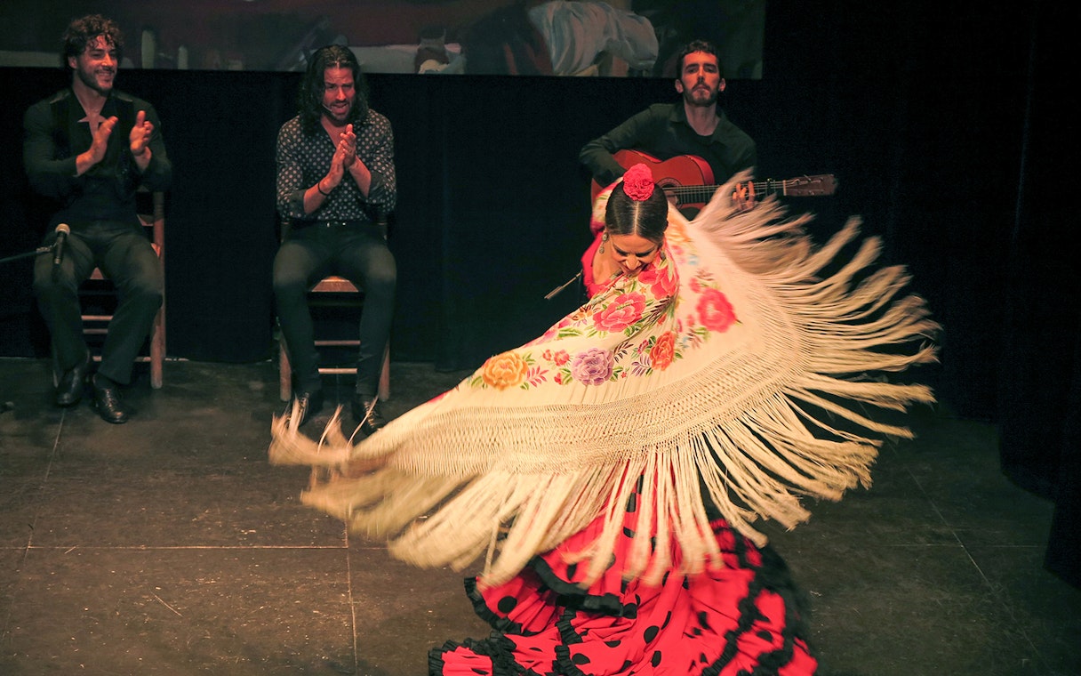 Flamenco dancer performing with musicians at Teatro Flamenco Triana.