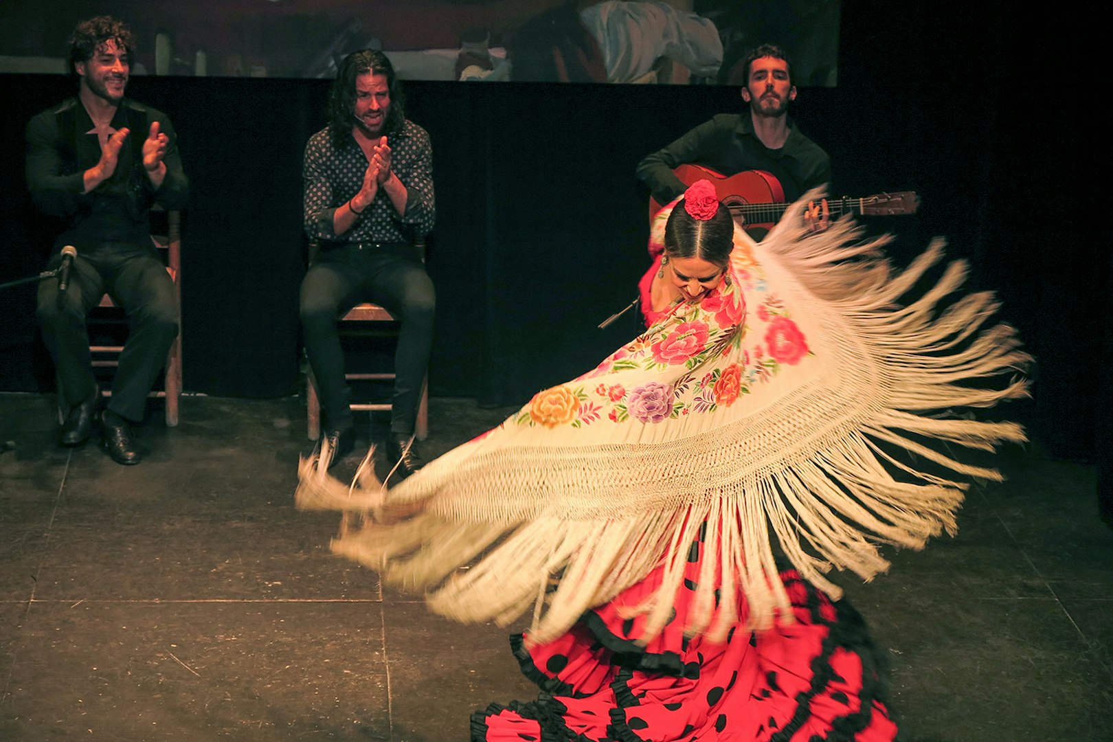 Flamenco dancer performing with musicians at Teatro Flamenco Triana.
