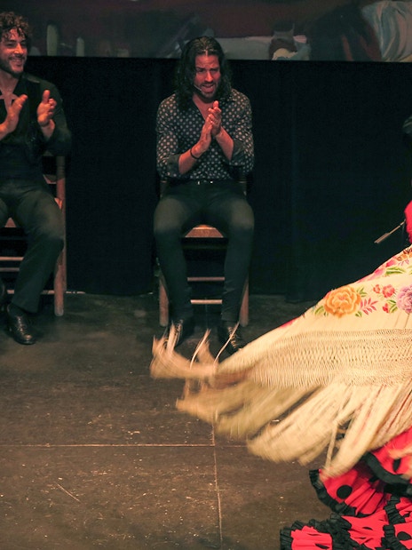 Flamenco dancer performing with musicians at Teatro Flamenco Triana.