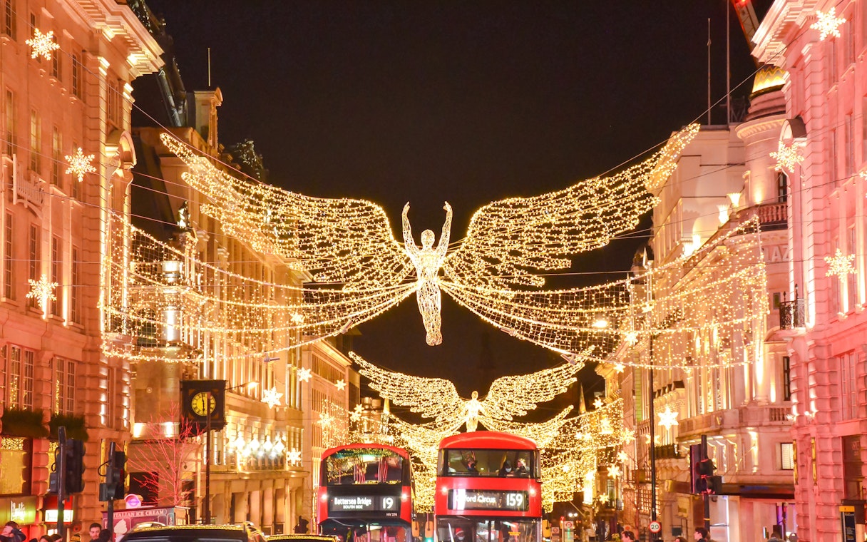Christmas lights and angel decorations on Regent Street, London, with red double-decker buses below.