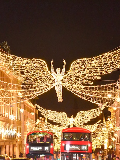Christmas lights and angel decorations on Regent Street, London, with red double-decker buses below.