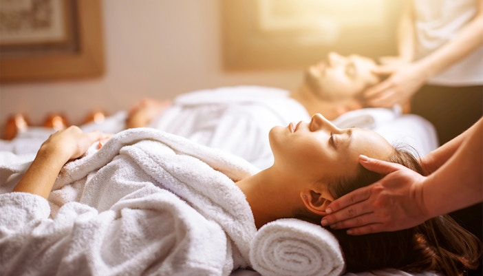 Couple receiving head massages at a spa.