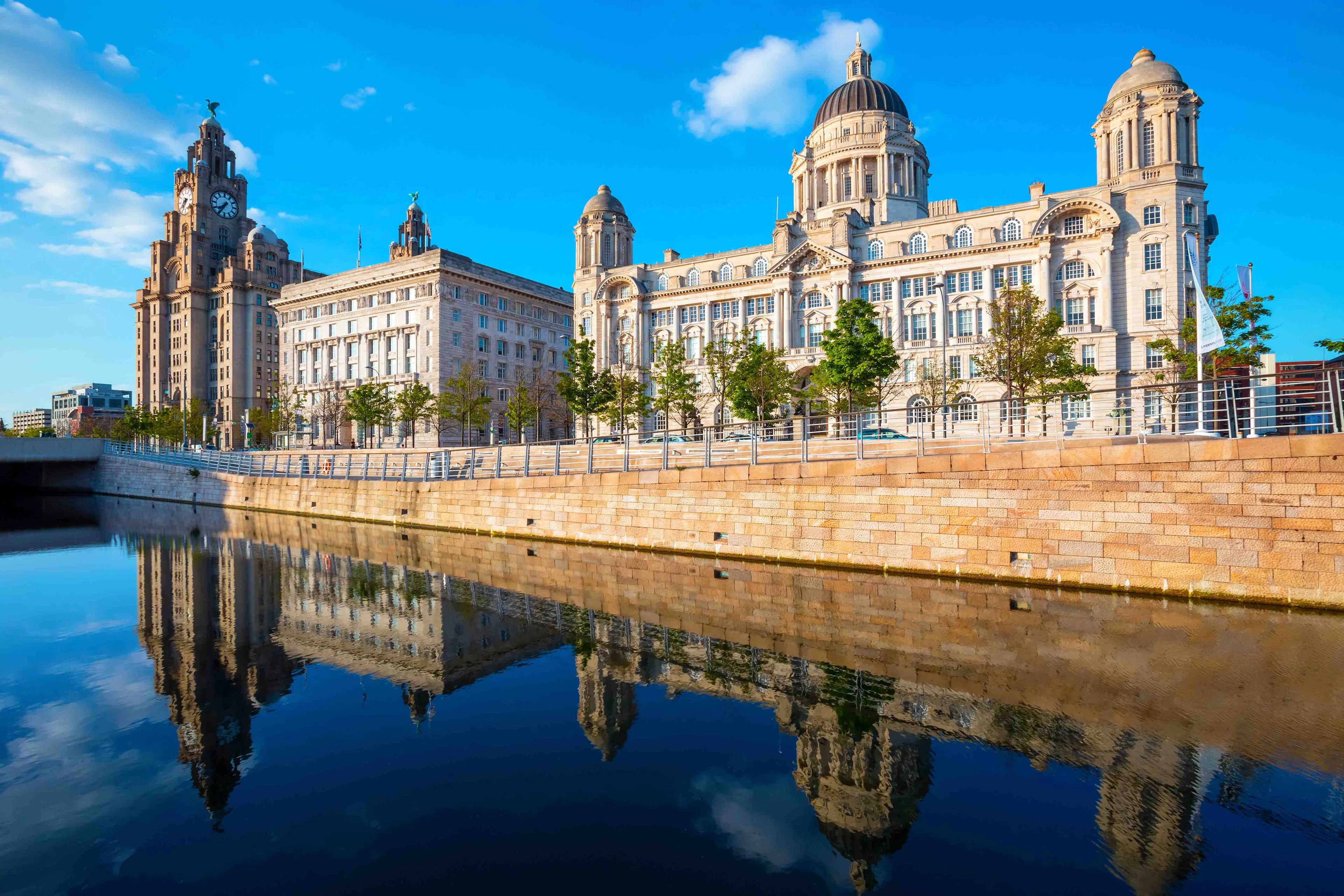 Liverpool riverfront with historic buildings reflected in the water.