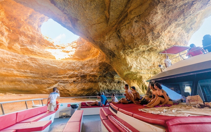 Boat tour inside Benagil Caves, Algarve, Portugal, with tourists observing rock formations.