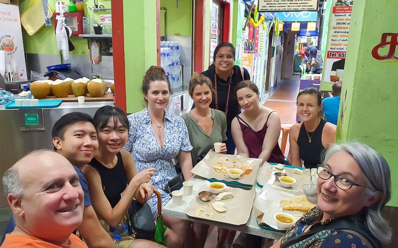 Group enjoying food at a table on a guided tasting tour in Little India Hawker Street, Singapore.
