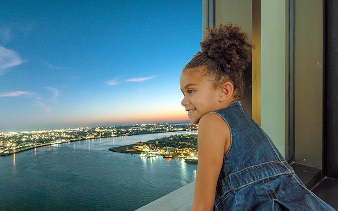 Child enjoying sunset view from Vue Orleans Observation Deck over Mississippi River.