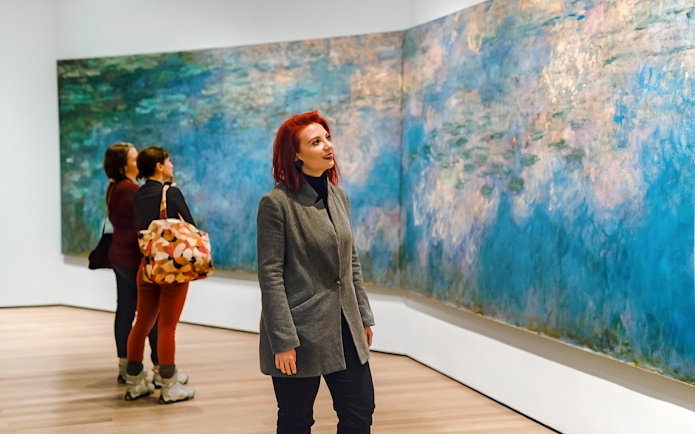 Visitors admiring Monet's Water Lilies at a museum exhibit.