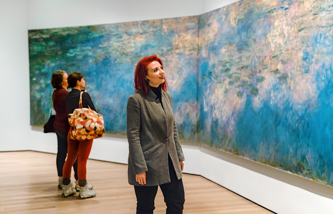 Visitors admiring Monet's Water Lilies at a museum exhibit.