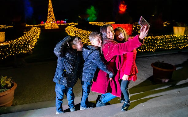 Guests taking a selfie at Warwick Castle Light Trail with festive lights in the background.