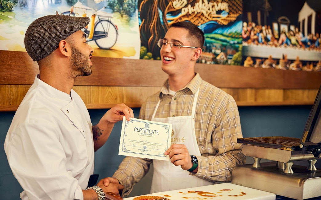 Man receiving certificate at Dutch syrup waffle workshop.
