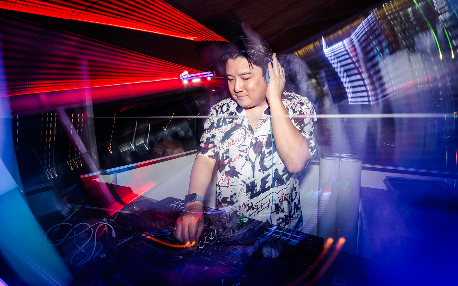 DJ performing live with colorful lights in a vibrant club setting.