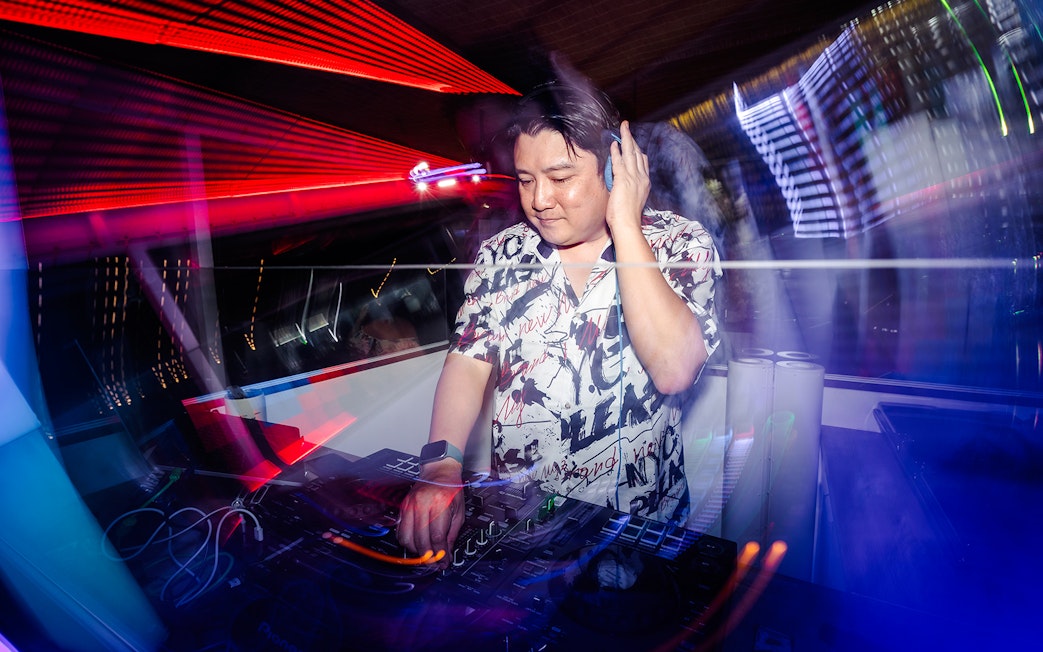 DJ performing live with colorful lights in a vibrant club setting.