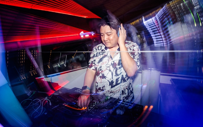 DJ performing live with colorful lights in a vibrant club setting.