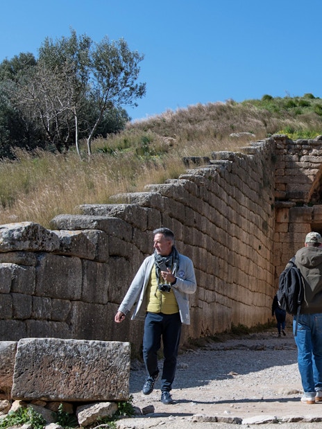 Visitors exploring the entrance of the Treasury of Atreus at Mycenae, Greece.