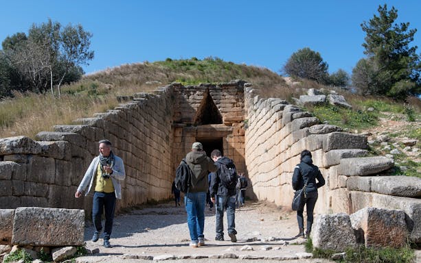 Visitors exploring the entrance of the Treasury of Atreus at Mycenae, Greece.