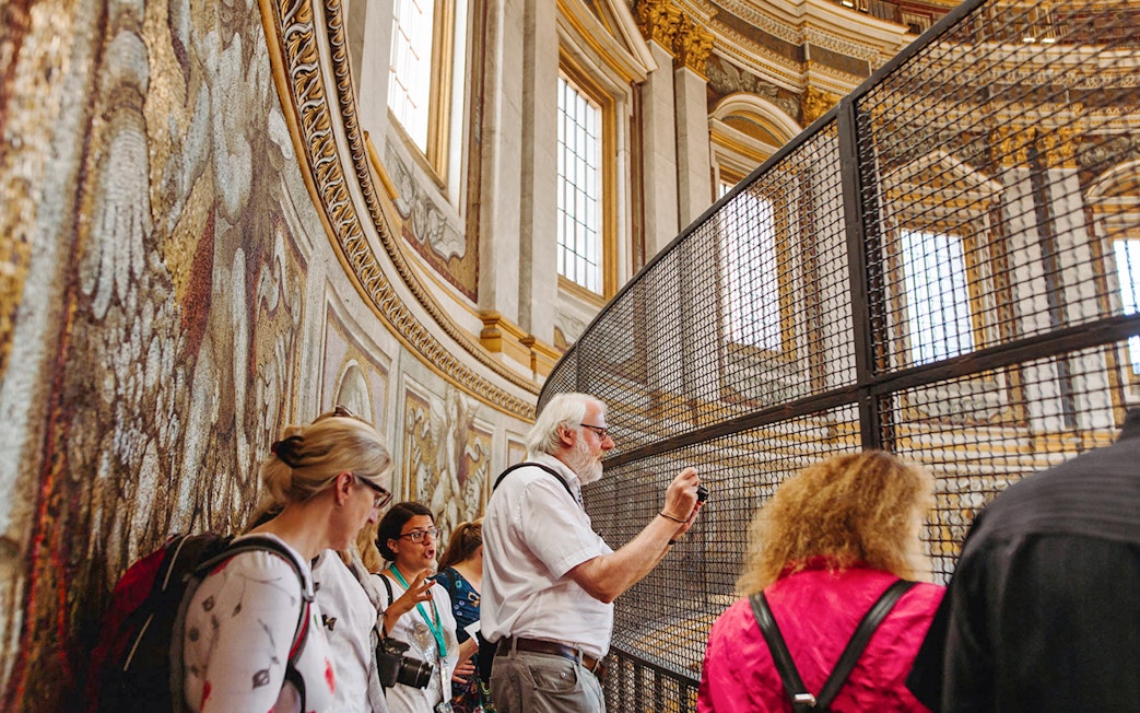 Tour group exploring the interior of St. Peter’s Basilica, focusing on detailed mosaics.
