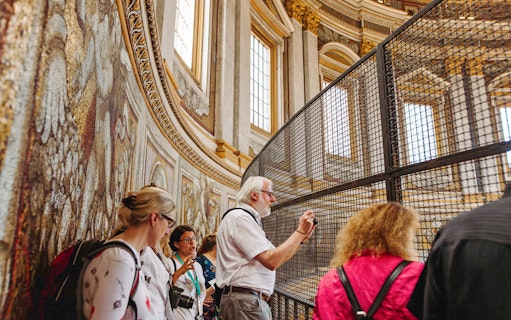 Tour group exploring the interior of St. Peter’s Basilica, focusing on detailed mosaics.