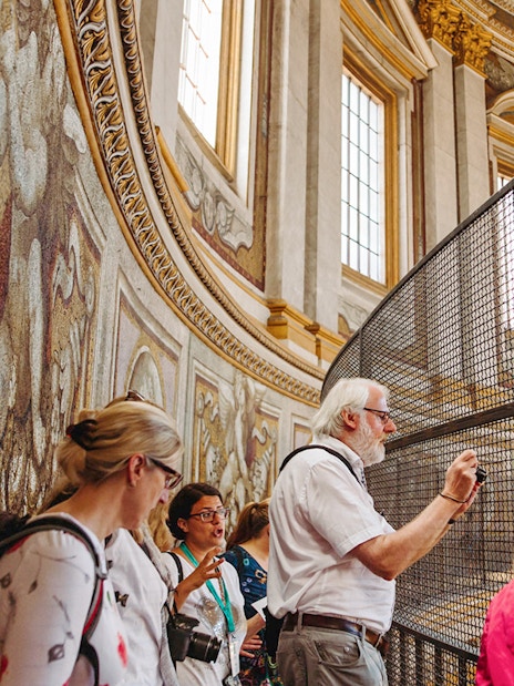 Tour group exploring the interior of St. Peter’s Basilica, focusing on detailed mosaics.