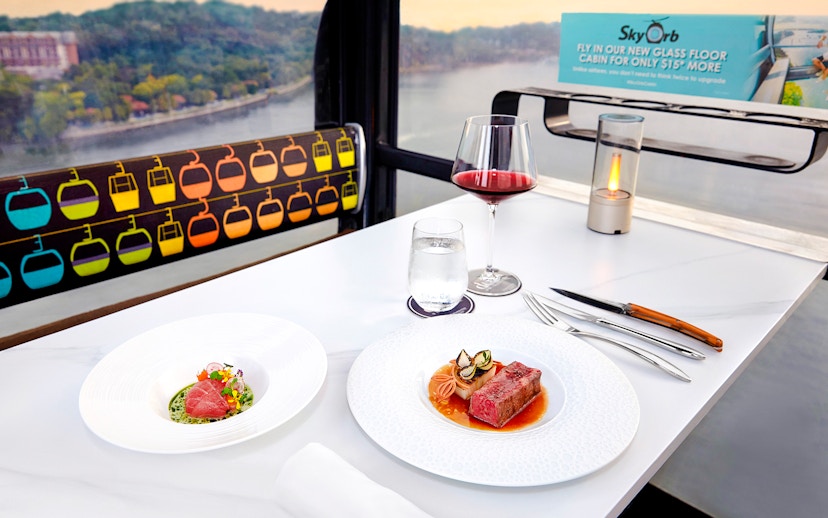 Singapore cable car dining with dishes by Chef Mathew Leong, overlooking cityscape.