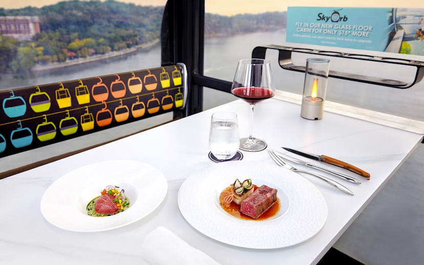 Singapore cable car dining with dishes by Chef Mathew Leong, overlooking cityscape.