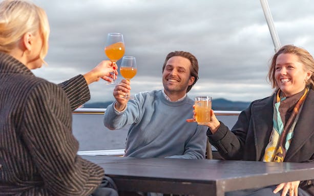 People enjoying drinks on a boat during the Oslo Brunch & Bubbles tour.