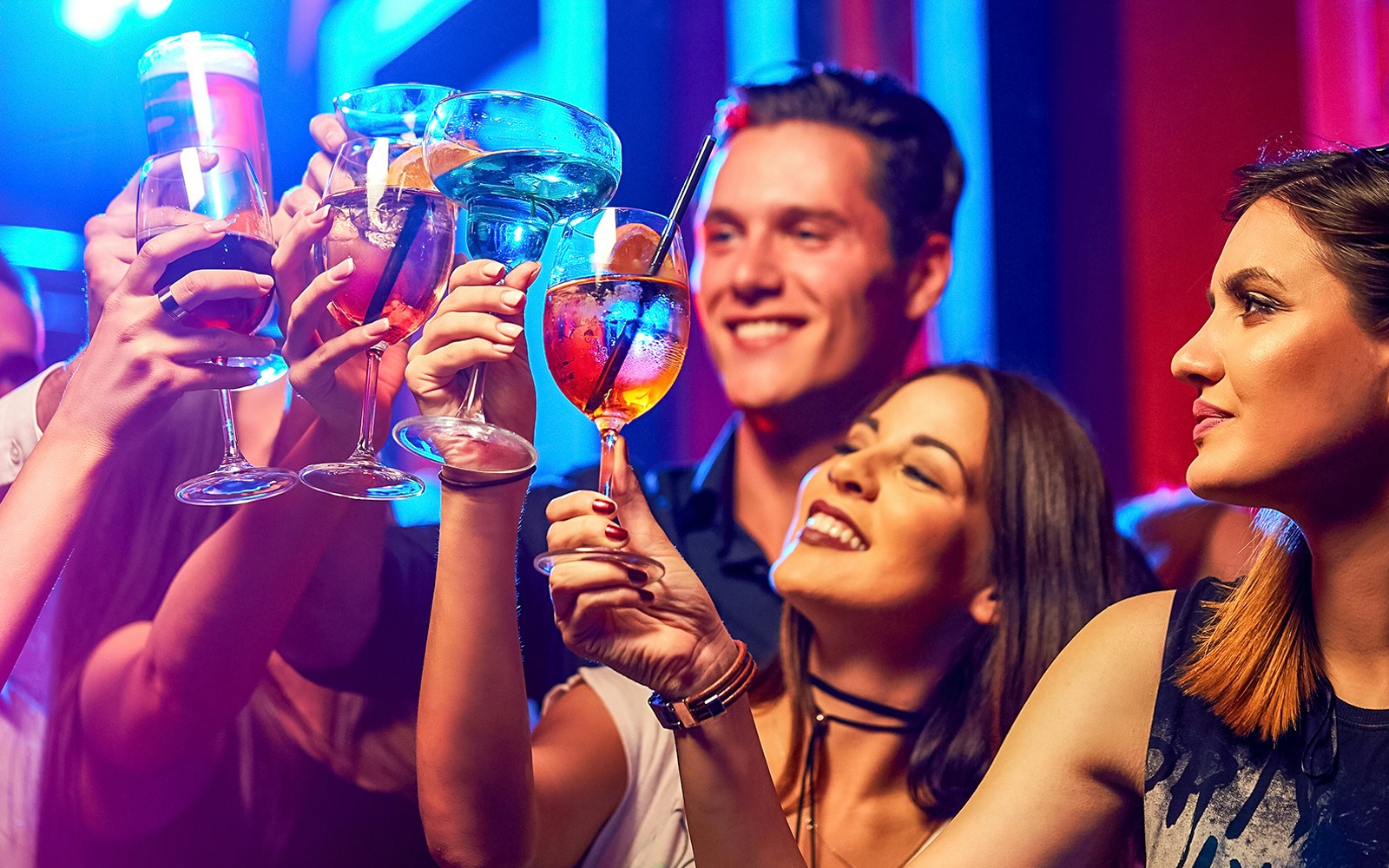 Friends raising glasses in a vibrant club setting.